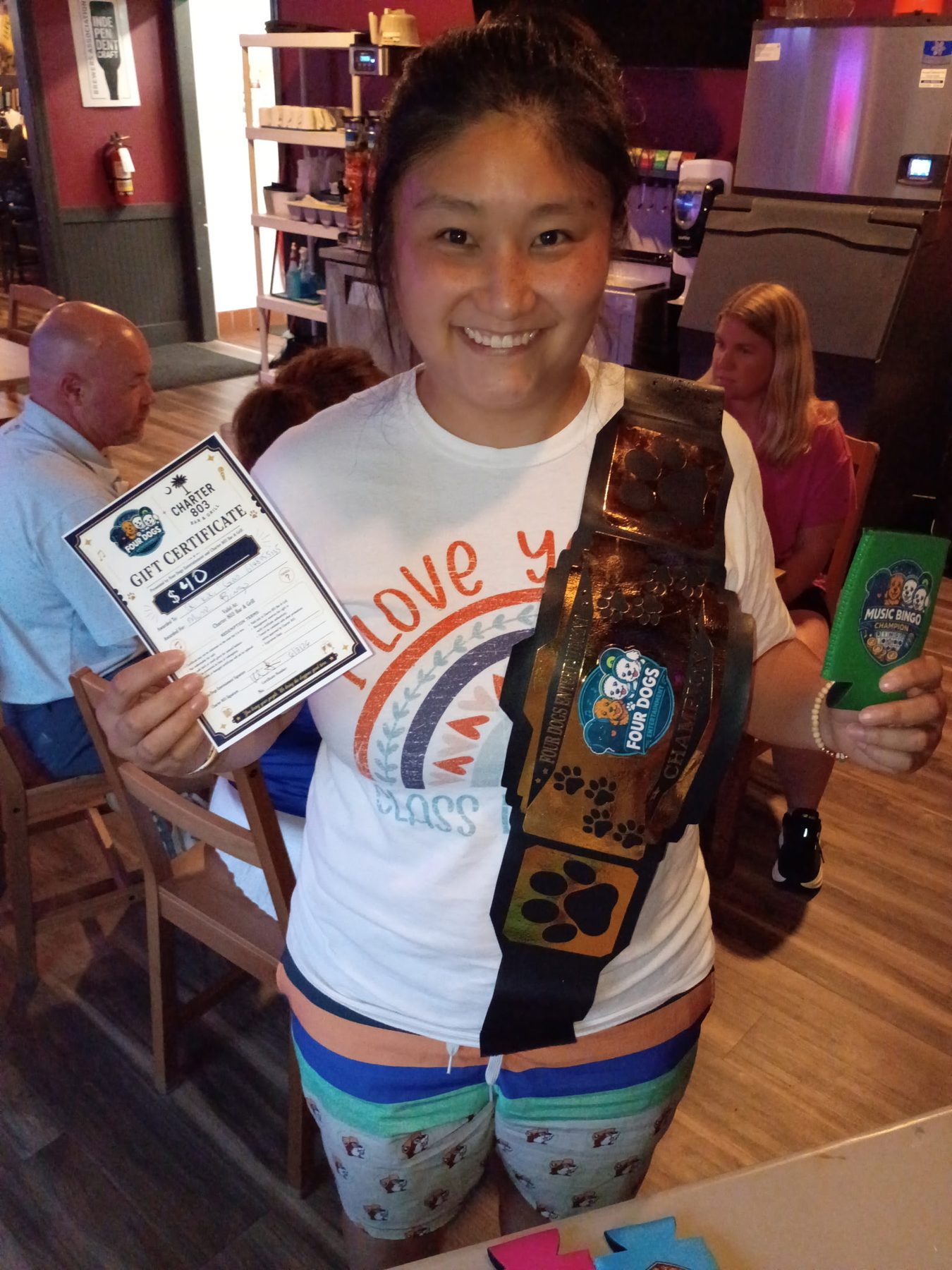 Music bingo champion holding the prize belt and gift certificate