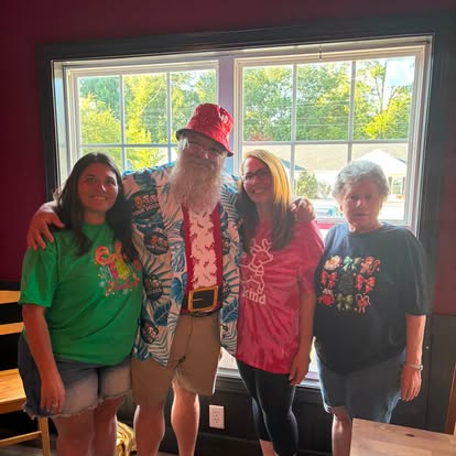 Santa Jim greeting guests at a Four Dogs holiday party