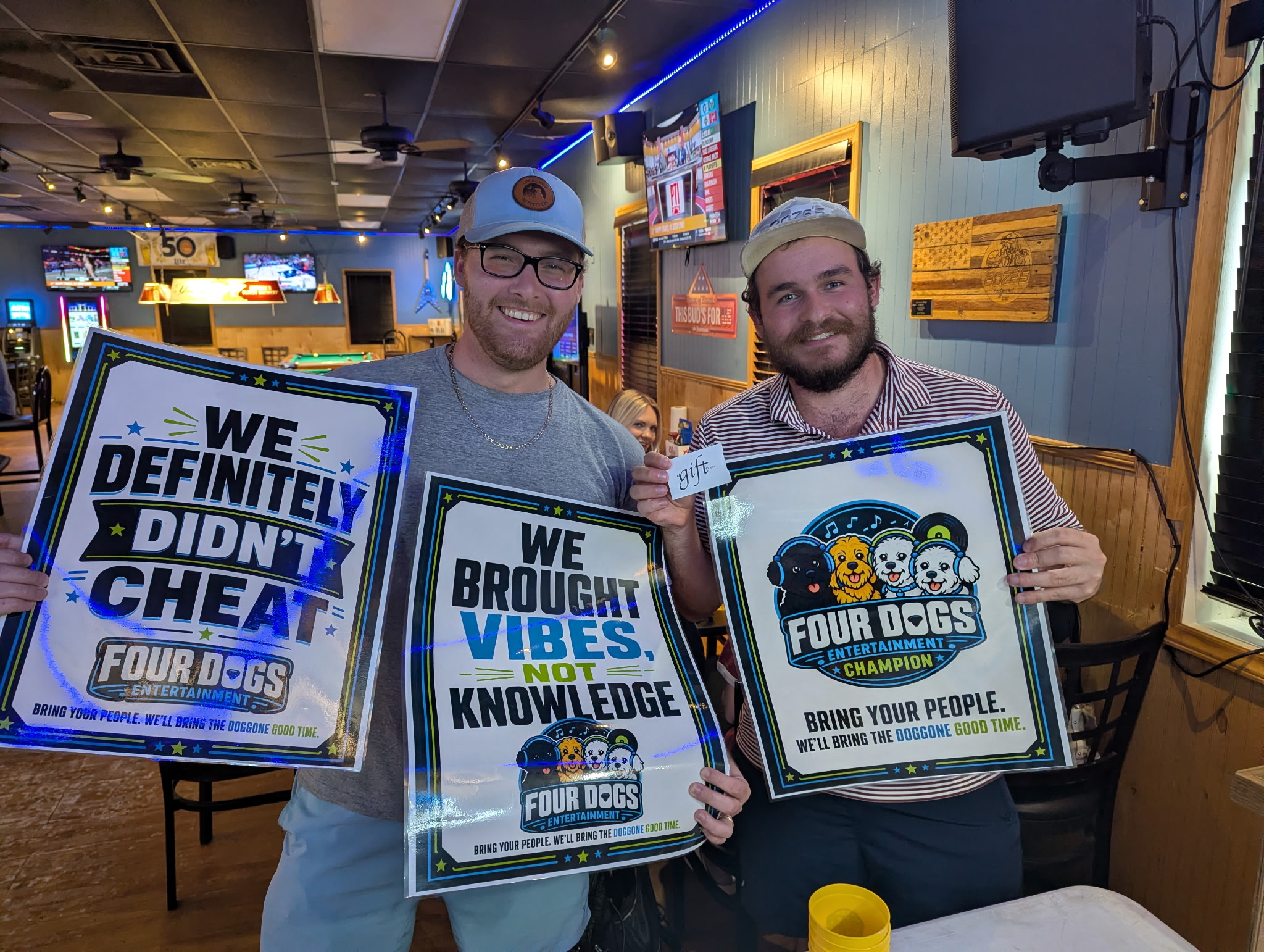 Two winners at Four Dogs Entertainment Survey Showdown at Boze’s Restaurant & Bar holding Four Dogs signs and a prize