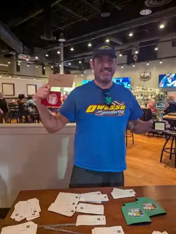 Four Dogs Entertainment trivia winner holding a first-place envelope and championship trophy at a venue event